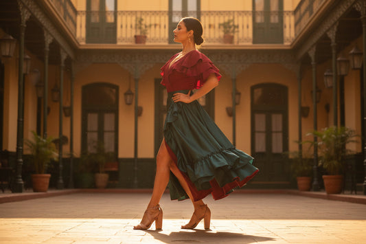 A woman in a ruffled off-shoulder dress and Piccadilly Ref 727047 RadiantGlide Special Occasion Glamorous Sandal Glitter Rose Gold (released Nov 2023) poses gracefully in a sunlit courtyard with arched windows, potted plants, and ornate railings.